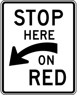 Stop Here on Red sign: white rectangle reading STOP HERE ON RED with an arrow pointing down and to the left.